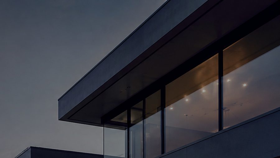 A contemporary building at dusk overlooking a lit city.